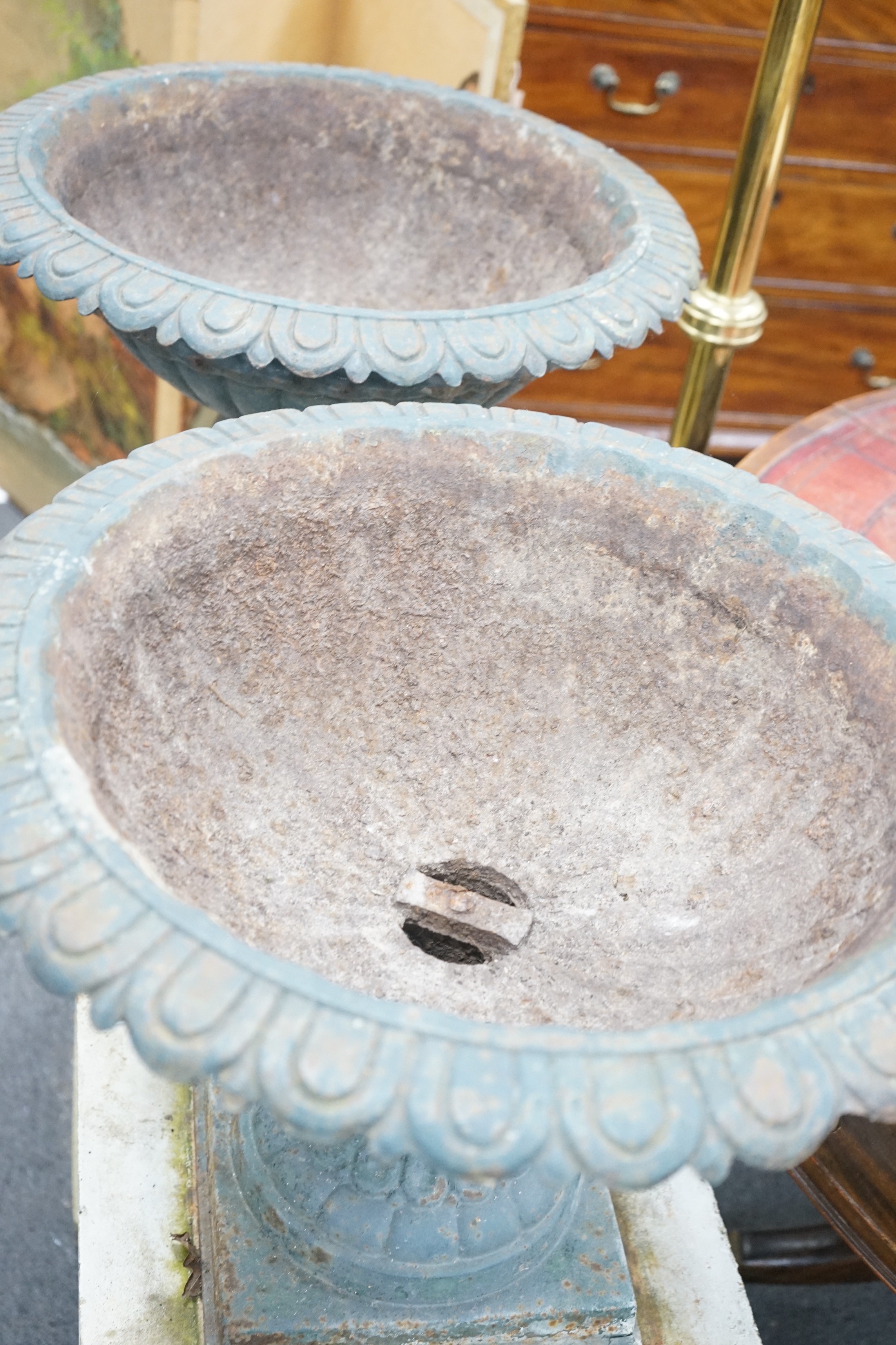 A pair of Victorian painted cast iron campana garden urns on square stone plinths, diameter 51cm, height including plinths 99cm